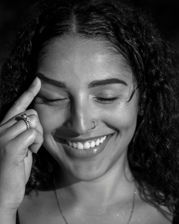 Monochrome Photo of Smiling Woman Touching Her Eyebrow